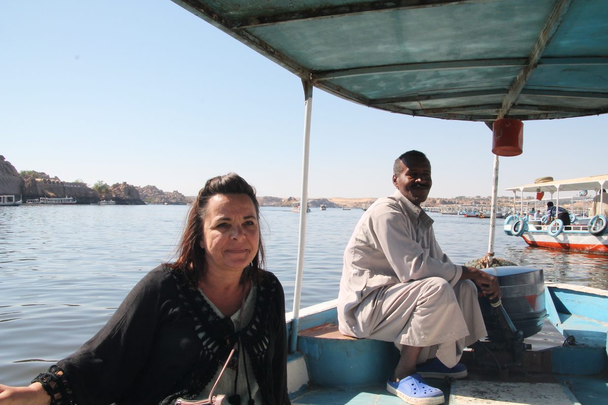 Don't Take Our Word For It - 7 - EZ TOUR EGYPT A woman travelling with EZ Tour Egypt sitting under the shade canopy of a Nile boat beside her Egyptian boatman near Aswan