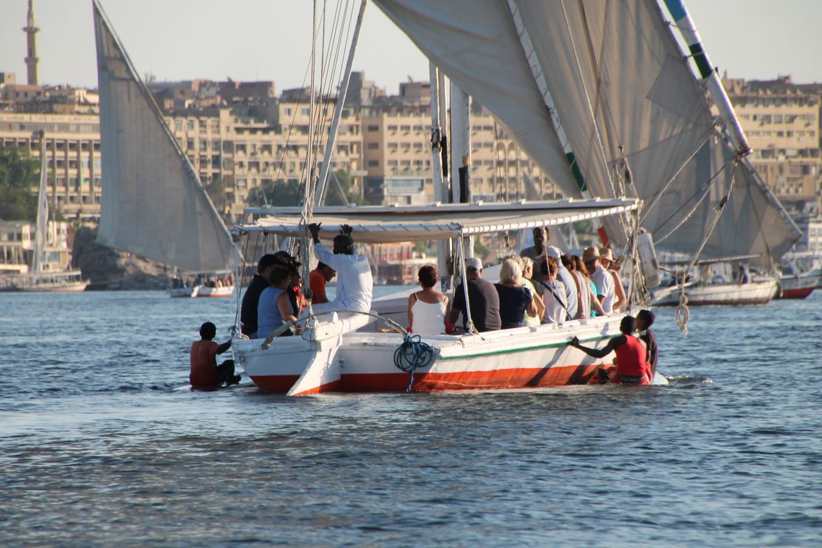 Don't Take Our Word For It - 9 - EZ TOUR EGYPT A group of travellers sailing a traditional felucca on the Nile past the Aswan waterfront