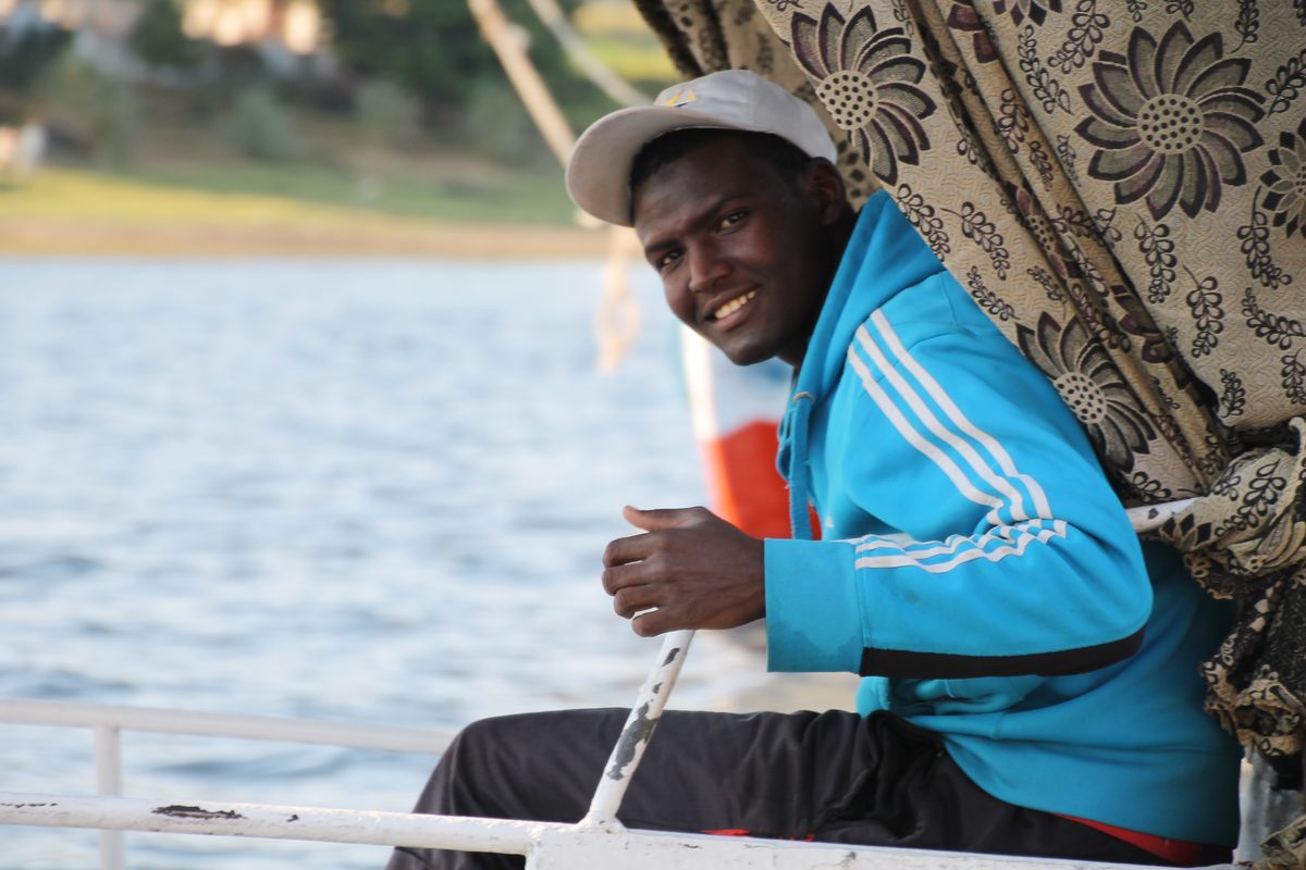 Don't Take Our Word For It - 8 - EZ TOUR EGYPT A young Egyptian crew member smiling at the tiller of a felucca on the Nile
